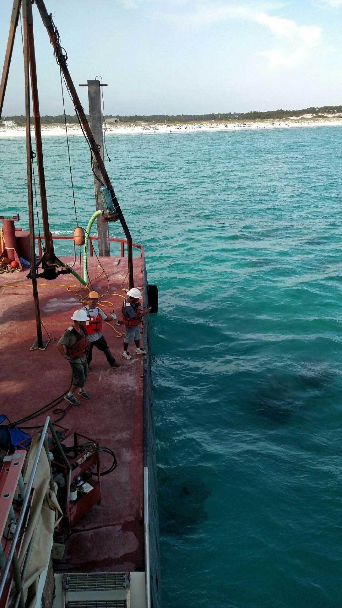 View from a work vessel toward crane rigging over clear water