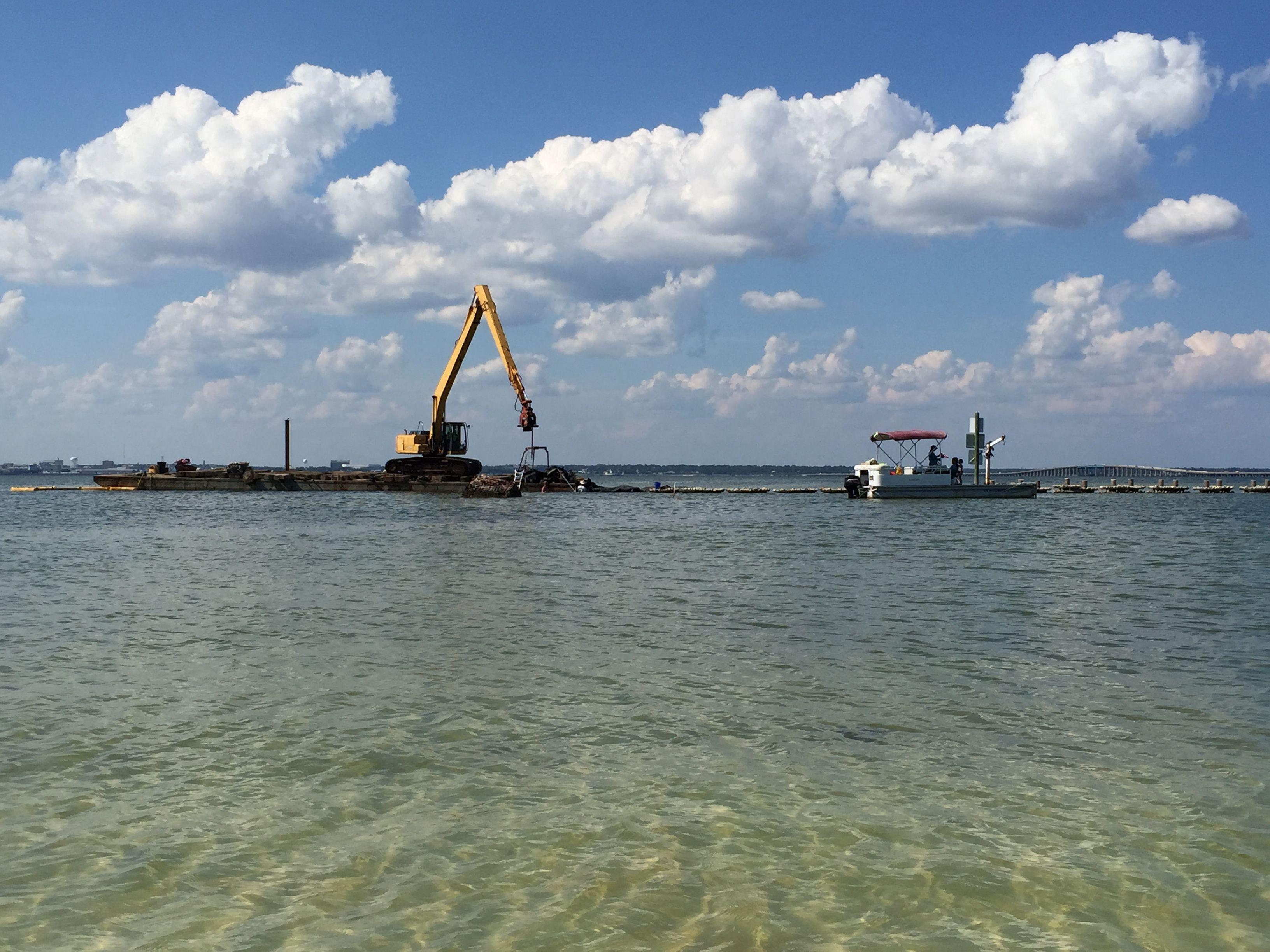 Crane and work vessels positioned offshore during reef deployment