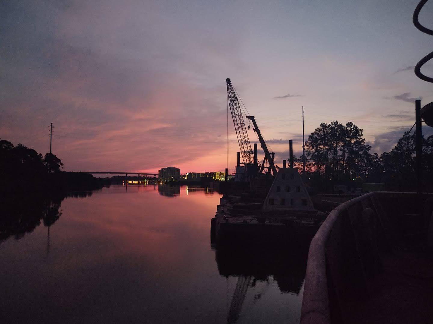 Crane barge silhouetted on a waterway at sunset