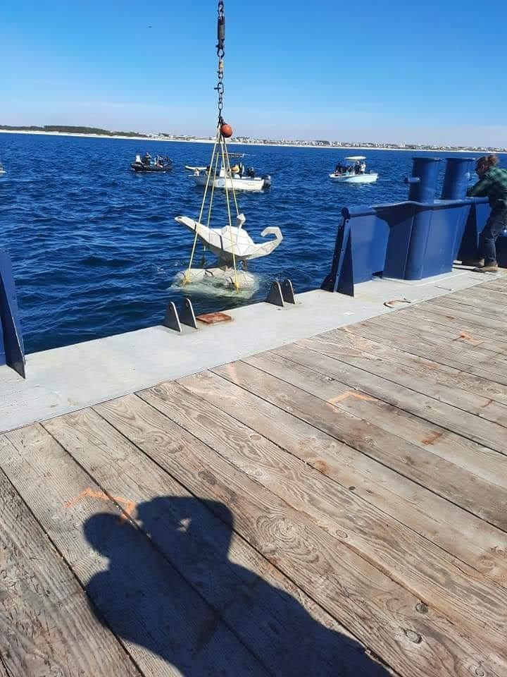 Small artificial reef structure suspended over water behind a vessel
