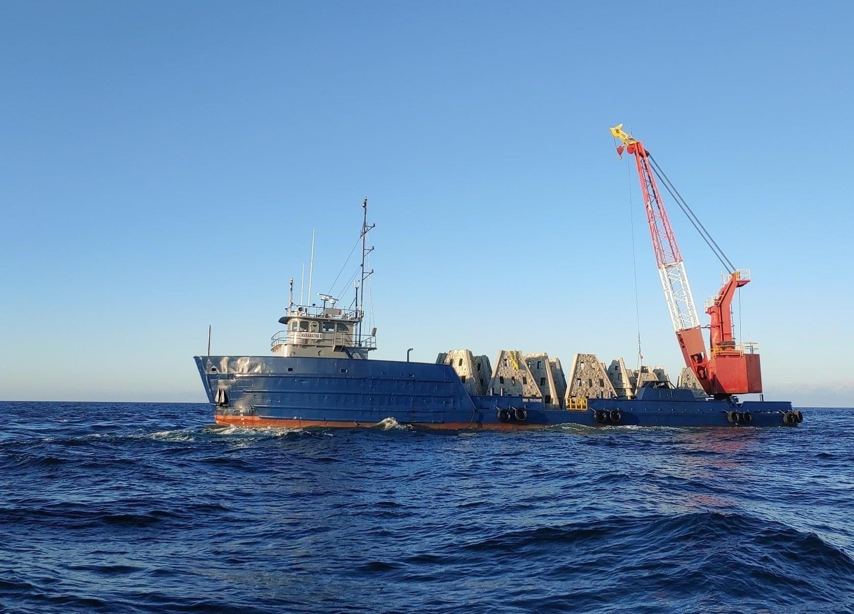 Crane vessel transporting concrete artificial reef modules offshore